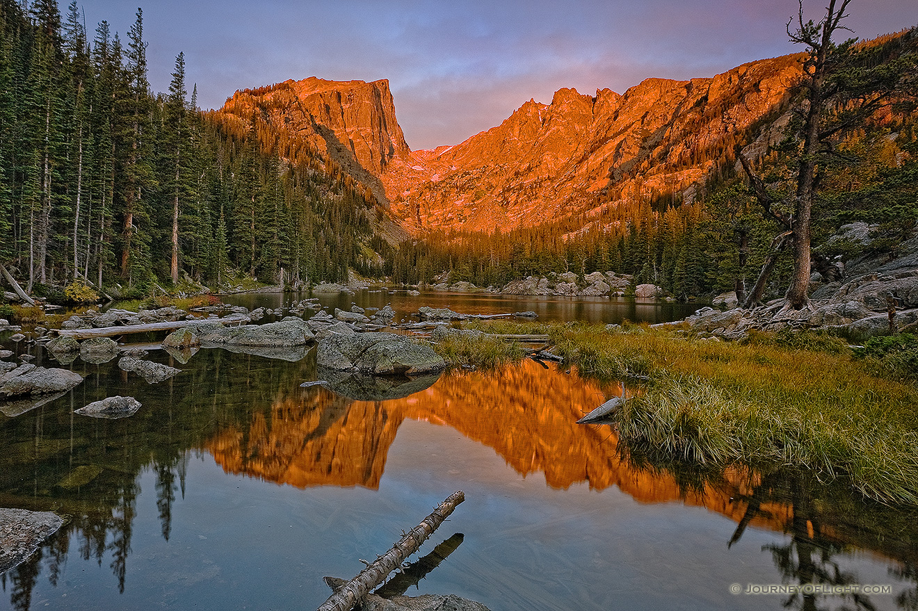 Still and peaceful, Dream Lake in Rocky Mountain National Park reflects an image of the majestic Hallett Peak while it glows red with the light of the rising sun. - Rocky Mountain NP Picture